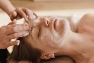 A close-up of a woman receiving a soothing facial massage with a skincare mask.